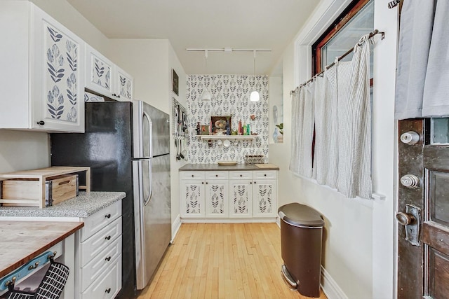 kitchen with stainless steel fridge, rail lighting, white cabinetry, butcher block counters, and light hardwood / wood-style floors