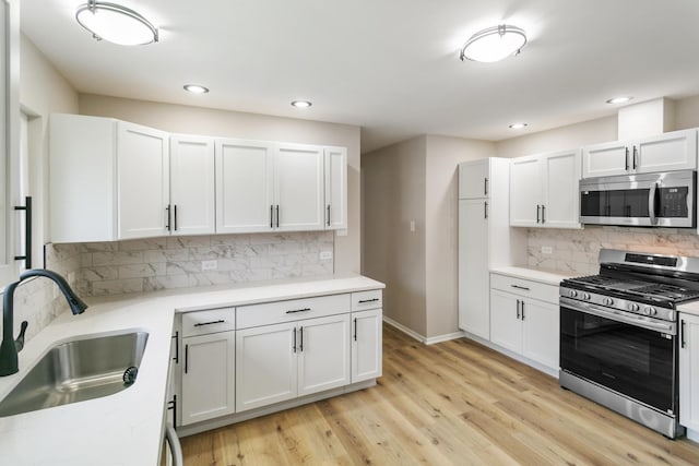 kitchen with sink, light hardwood / wood-style flooring, white cabinetry, stainless steel appliances, and tasteful backsplash