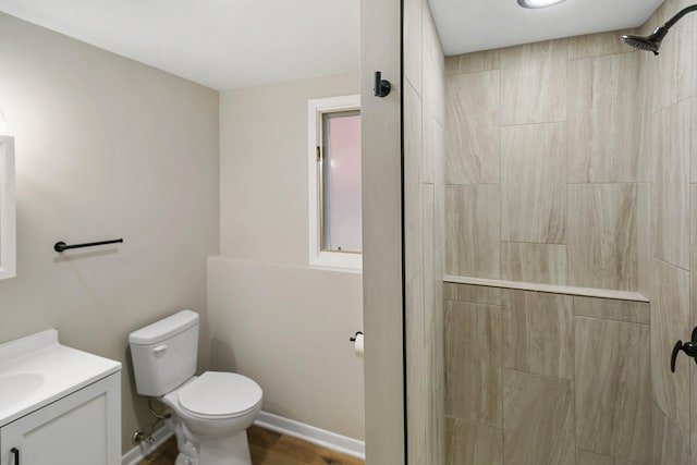 bathroom featuring tiled shower, vanity, and toilet