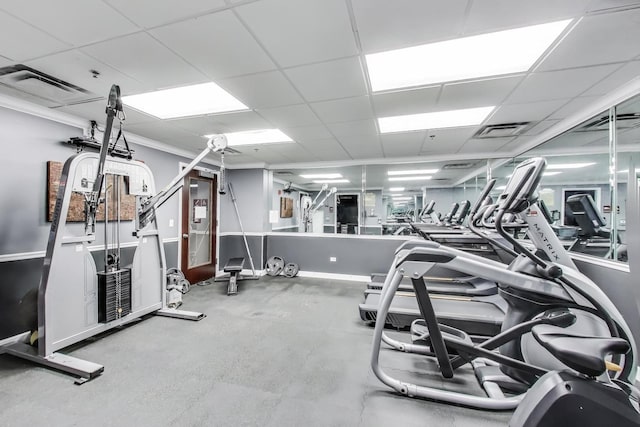 exercise room with a paneled ceiling, visible vents, and crown molding