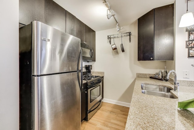 kitchen featuring stainless steel appliances, light countertops, a sink, and light wood-style flooring