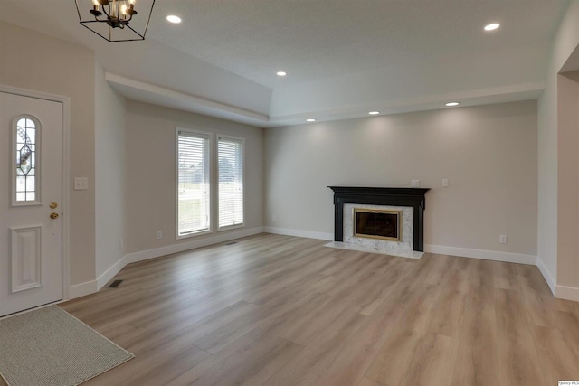 unfurnished living room with recessed lighting, baseboards, a chandelier, light wood-style floors, and a fireplace