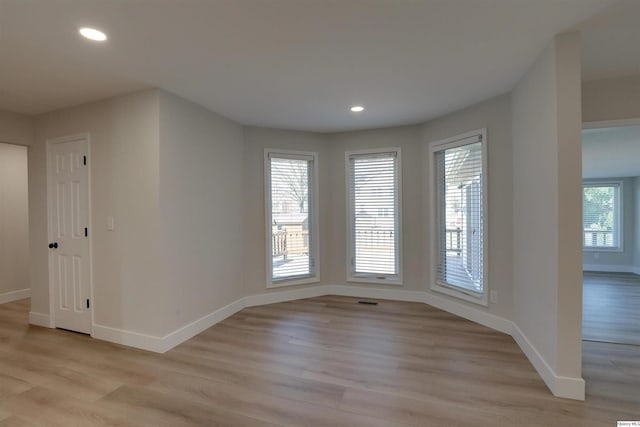 spare room with baseboards, light wood-style floors, and recessed lighting