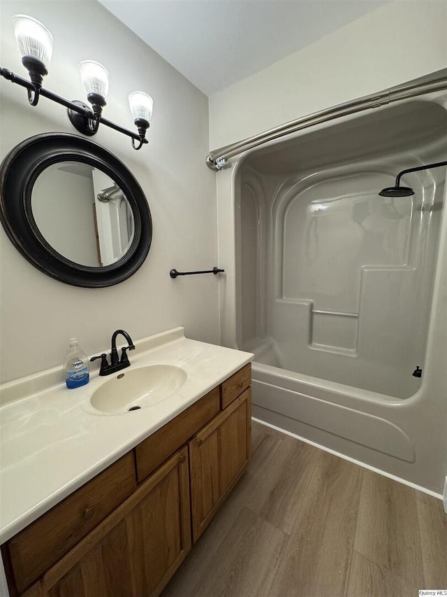 bathroom featuring wood-type flooring,  shower combination, and vanity