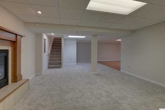 finished below grade area featuring carpet, baseboards, stairs, and a paneled ceiling