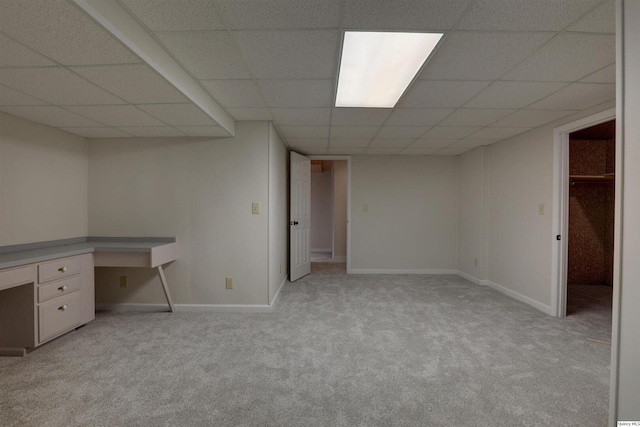 finished basement with baseboards, a paneled ceiling, and light colored carpet