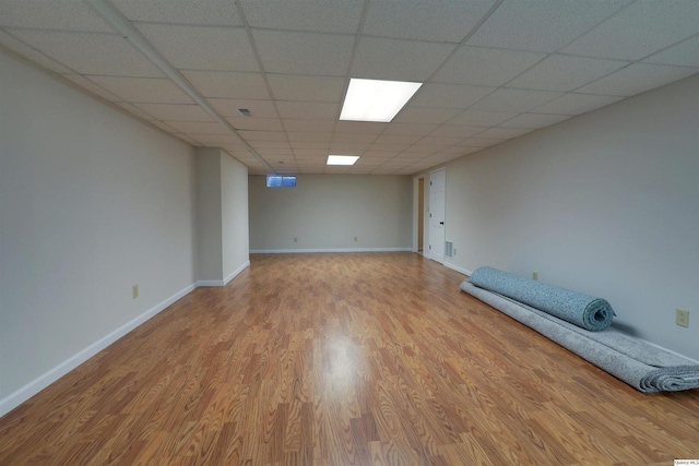 finished basement with baseboards, wood finished floors, and a paneled ceiling