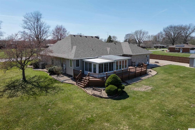 rear view of property with a shingled roof, a yard, and a deck