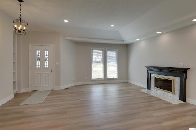 unfurnished living room featuring a healthy amount of sunlight, a premium fireplace, and light wood-type flooring