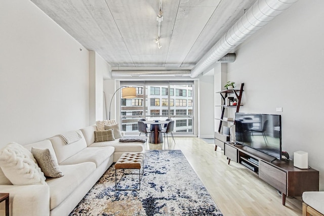 living room featuring expansive windows, rail lighting, and light hardwood / wood-style flooring