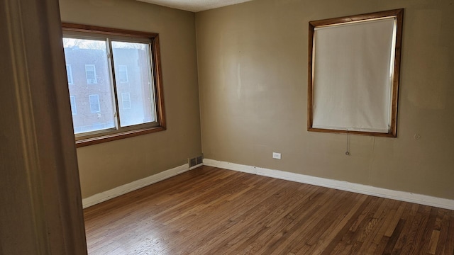 empty room with visible vents, baseboards, and wood finished floors