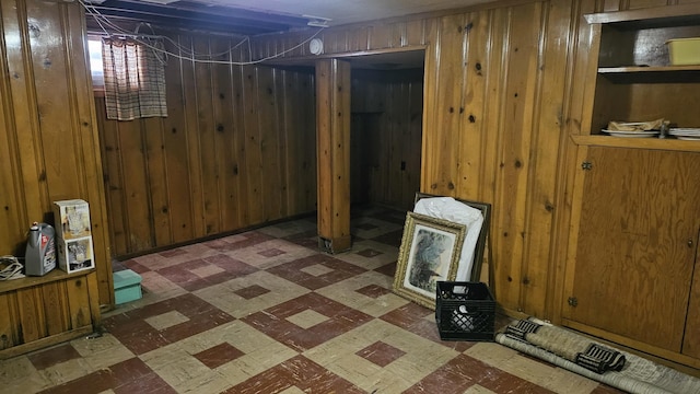 unfinished basement featuring dark floors and wooden walls