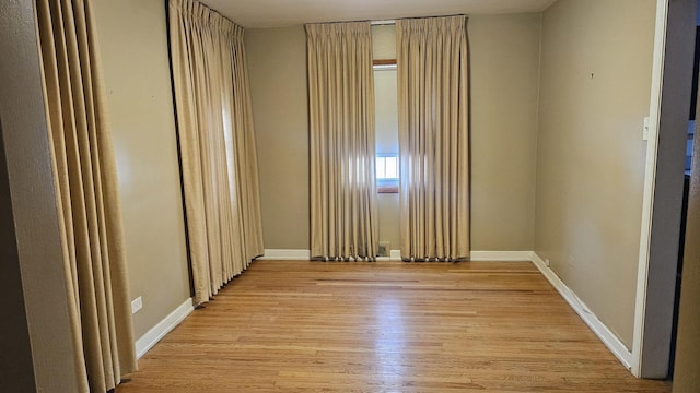 unfurnished room with light wood finished floors and baseboards