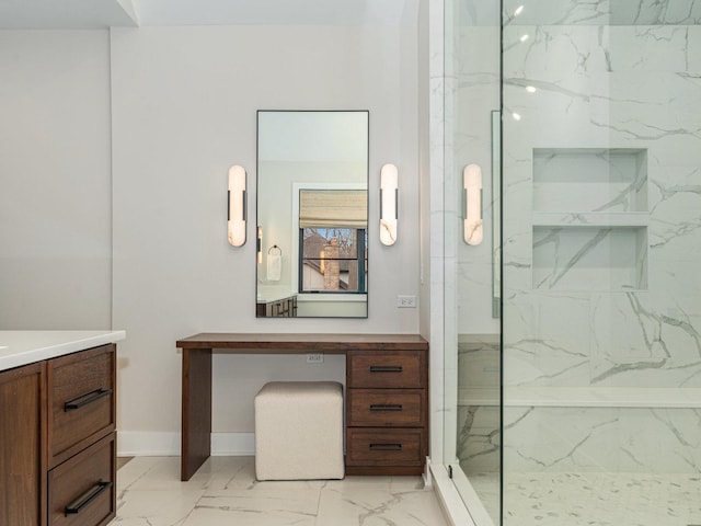 bathroom with marble finish floor, baseboards, vanity, and a marble finish shower