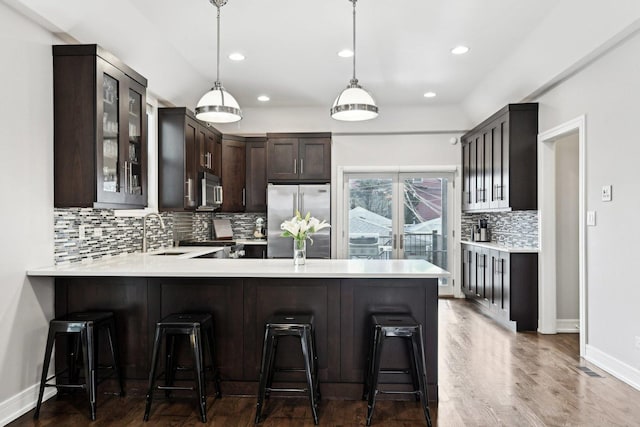 kitchen featuring a breakfast bar, sink, hanging light fixtures, kitchen peninsula, and stainless steel appliances