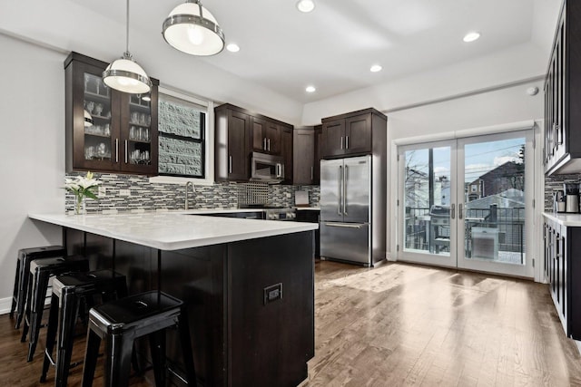 kitchen featuring appliances with stainless steel finishes, a breakfast bar, decorative light fixtures, tasteful backsplash, and kitchen peninsula