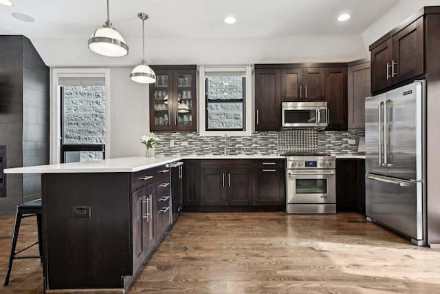 kitchen with pendant lighting, high quality appliances, a kitchen breakfast bar, dark brown cabinetry, and kitchen peninsula