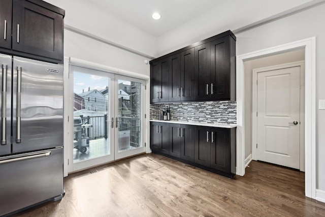 kitchen with tasteful backsplash, built in refrigerator, wood-type flooring, and french doors