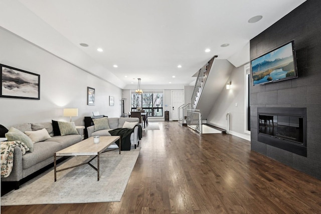 living room featuring a tile fireplace and dark wood-type flooring