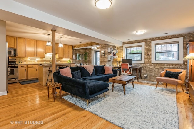 living room featuring brick wall and light wood-style flooring