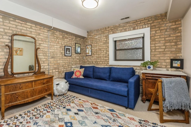 carpeted living area with brick wall and visible vents