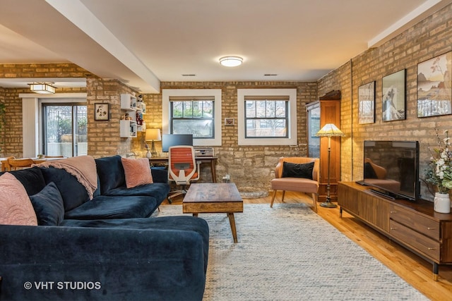 living area with brick wall, light wood finished floors, and a brick fireplace