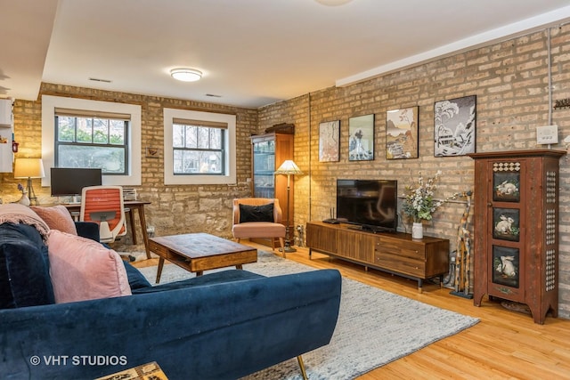 living room with brick wall and wood finished floors