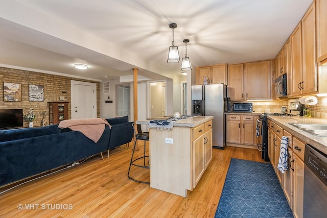 kitchen featuring open floor plan, stainless steel appliances, light wood finished floors, and light countertops