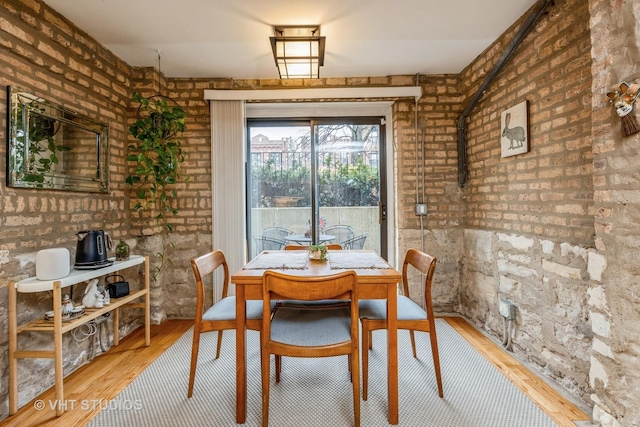 dining area with brick wall and wood finished floors