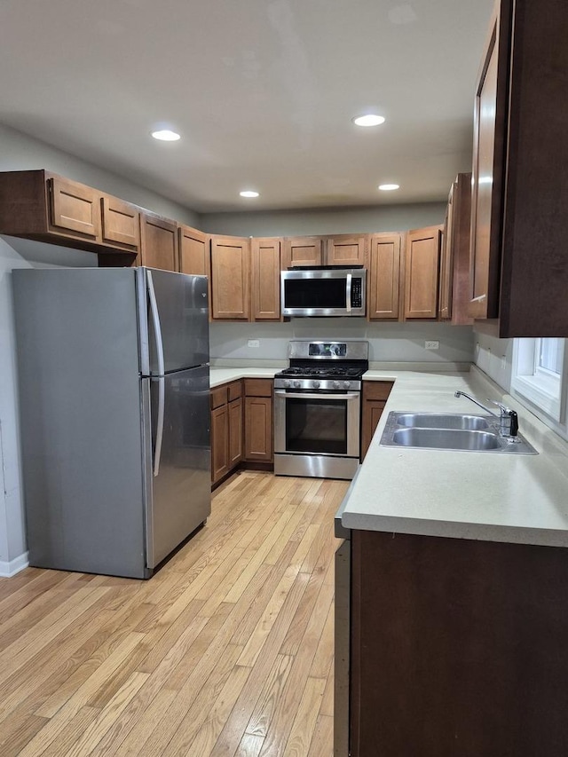 kitchen featuring stainless steel appliances, sink, and light hardwood / wood-style flooring