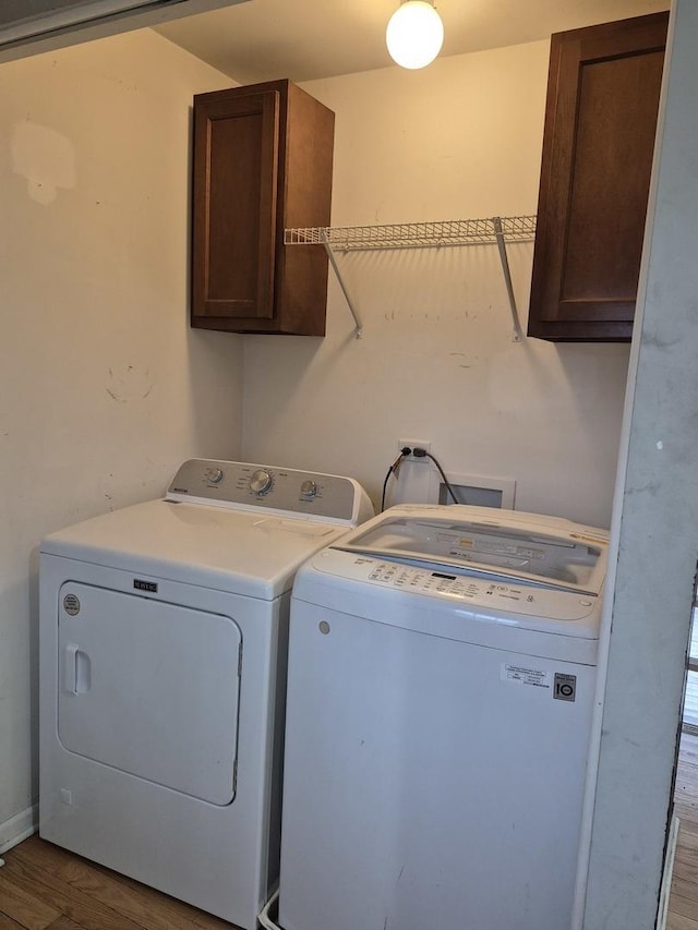 washroom featuring hardwood / wood-style flooring, cabinets, and separate washer and dryer