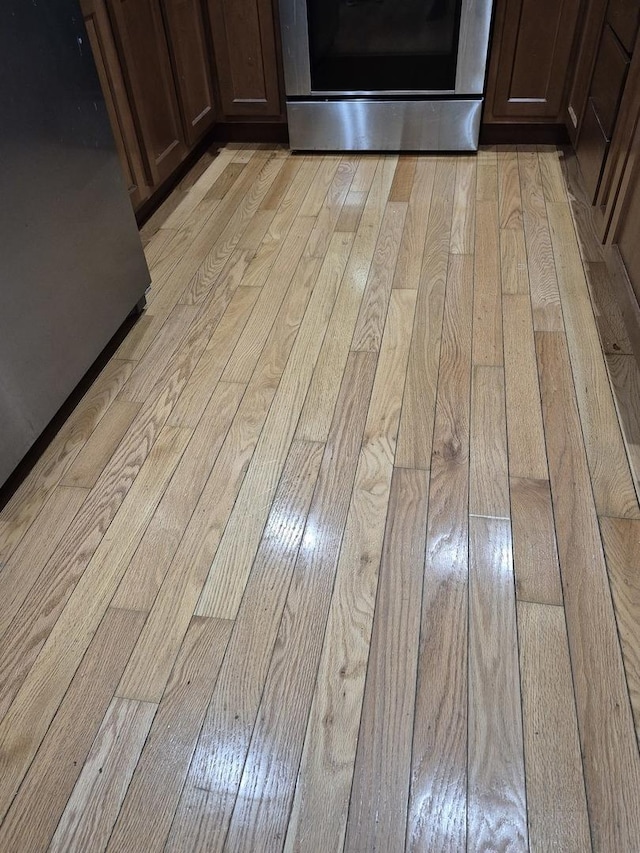 details with dark brown cabinets, light wood-type flooring, and range