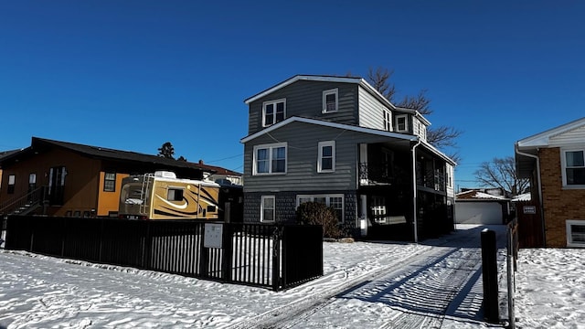 snow covered back of property with a garage