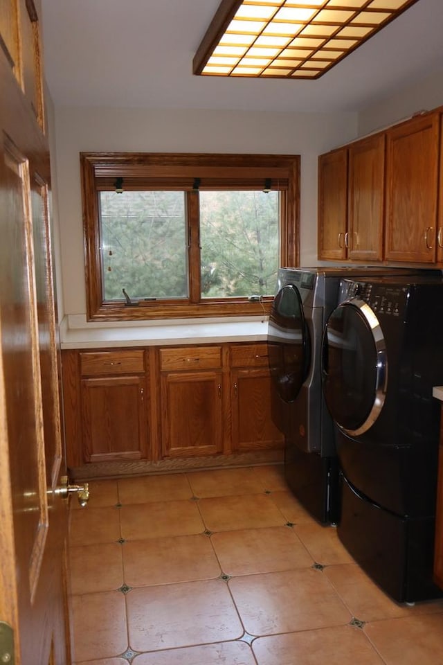 laundry room featuring cabinets, light tile patterned floors, and washer and clothes dryer