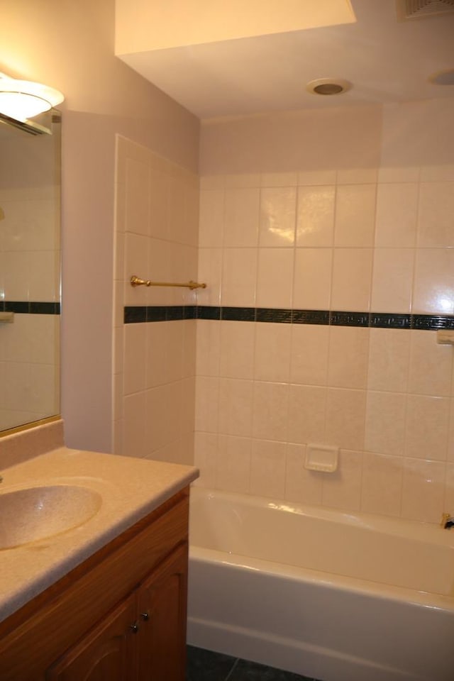 bathroom with tile patterned floors, vanity, and tiled shower / bath combo