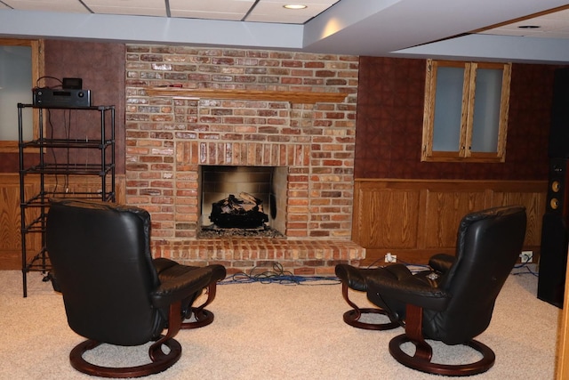 carpeted living room with a fireplace and wood walls