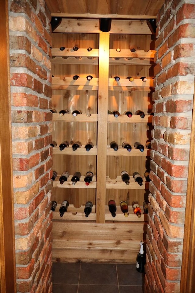 wine room featuring dark tile patterned flooring and brick wall