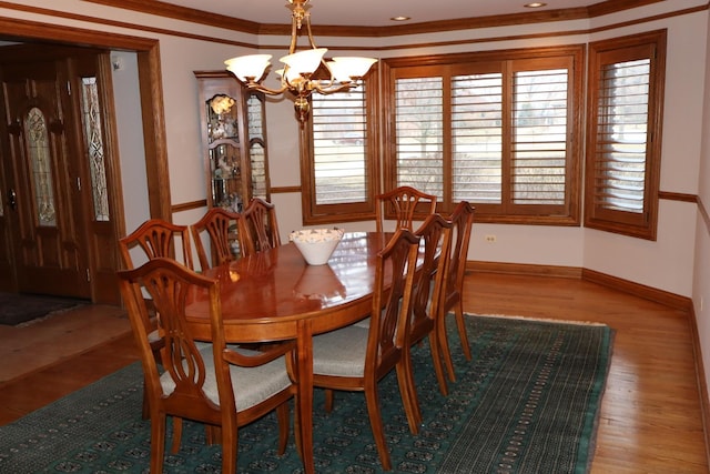 dining area with hardwood / wood-style floors, crown molding, and a chandelier