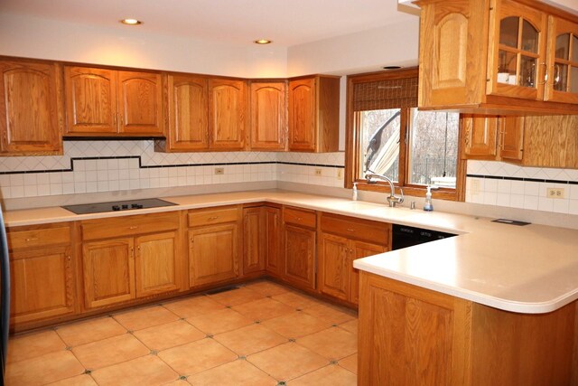 kitchen with backsplash, kitchen peninsula, sink, and black appliances