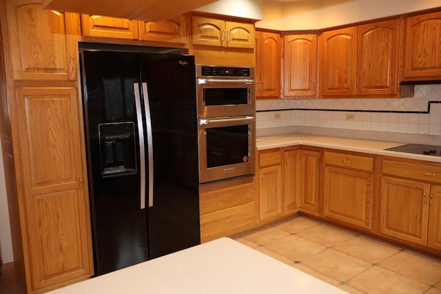 kitchen featuring tasteful backsplash, light tile patterned floors, and black appliances