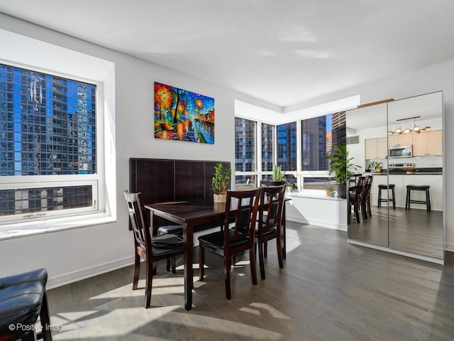 dining area featuring dark wood-type flooring, a city view, and baseboards