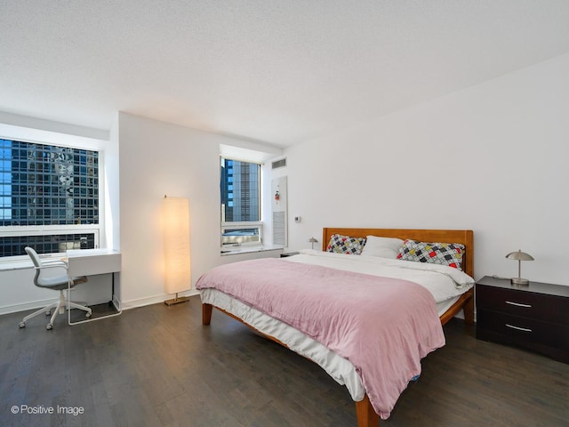 bedroom featuring baseboards, visible vents, dark wood finished floors, and a textured ceiling