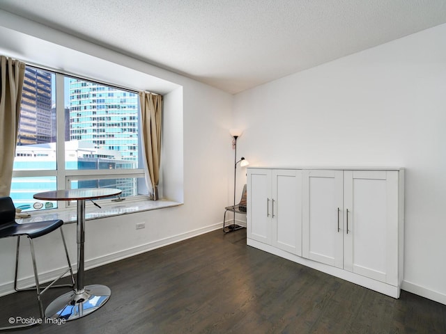 interior space featuring dark wood-style floors, a city view, a textured ceiling, and baseboards