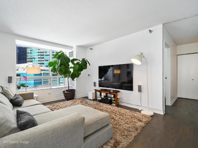 living room featuring dark wood-style flooring, a textured ceiling, and baseboards