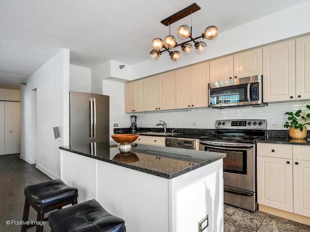 kitchen with backsplash, appliances with stainless steel finishes, pendant lighting, and a sink