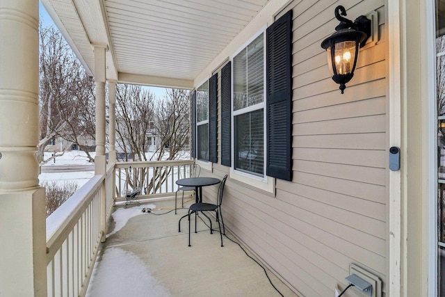 snow covered back of property with covered porch