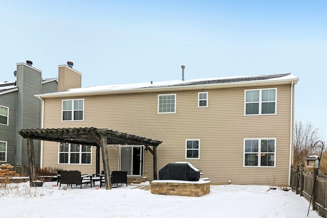 snow covered back of property with a pergola