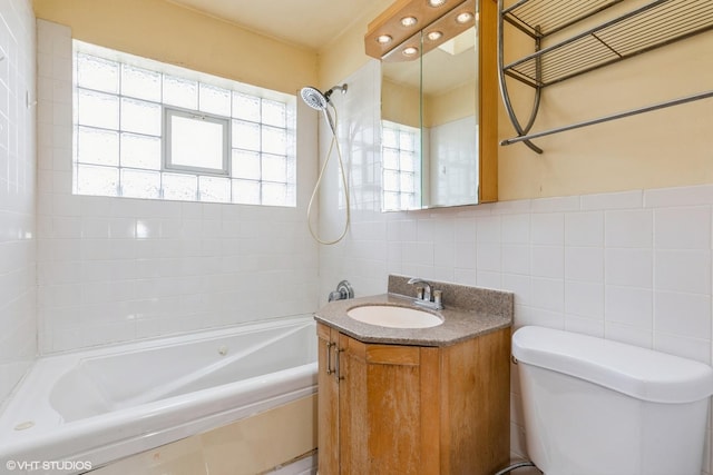 full bathroom featuring tiled shower / bath, vanity, toilet, and tile walls