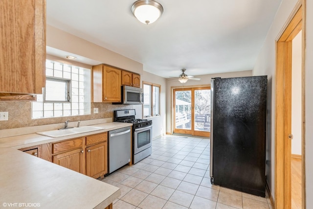 kitchen with sink, light tile patterned floors, appliances with stainless steel finishes, ceiling fan, and backsplash