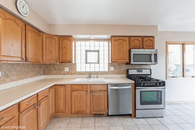 kitchen featuring tasteful backsplash, stainless steel appliances, sink, and light tile patterned floors